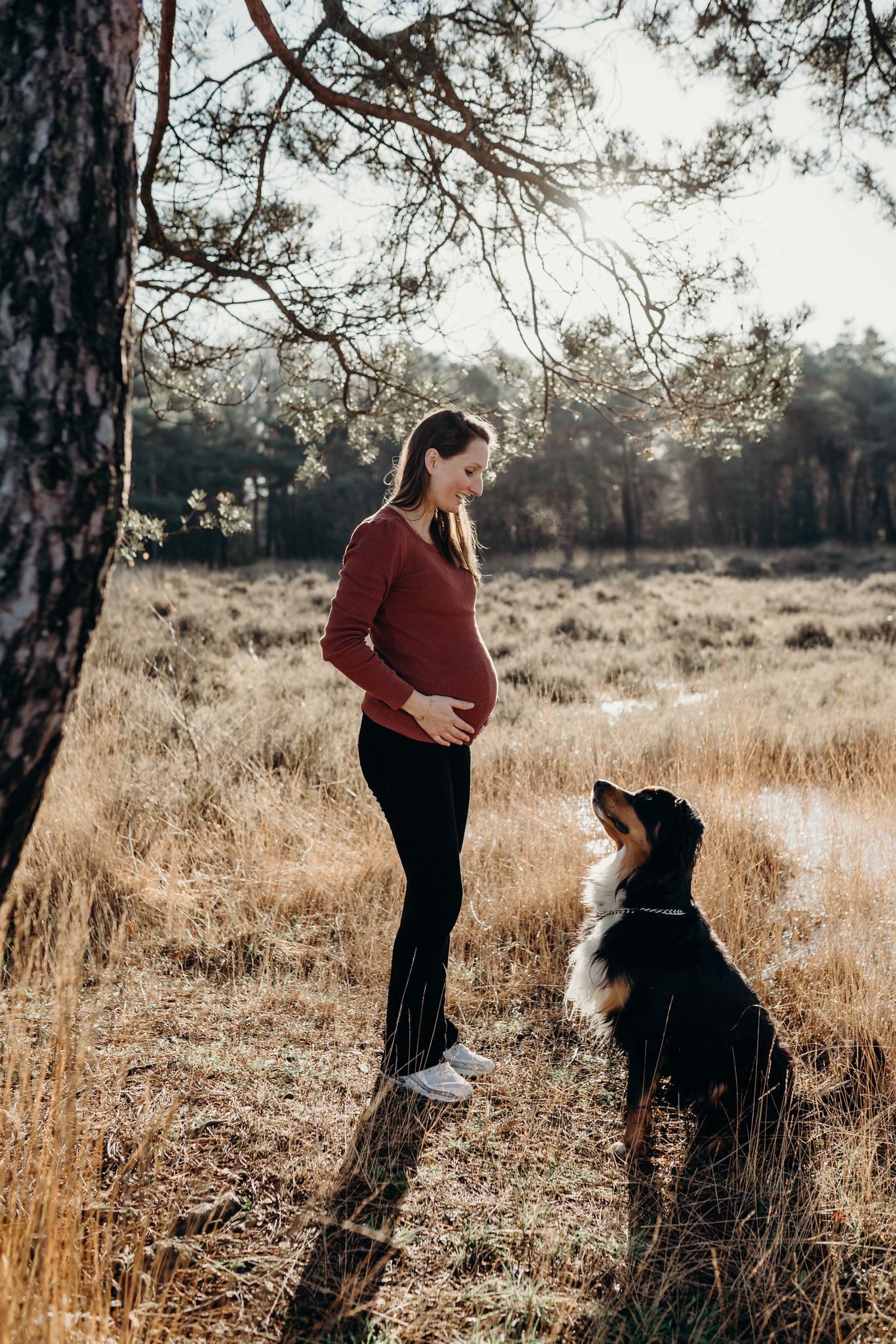 Tessa zwanger met hond tegenover haar. Buiten op de hei